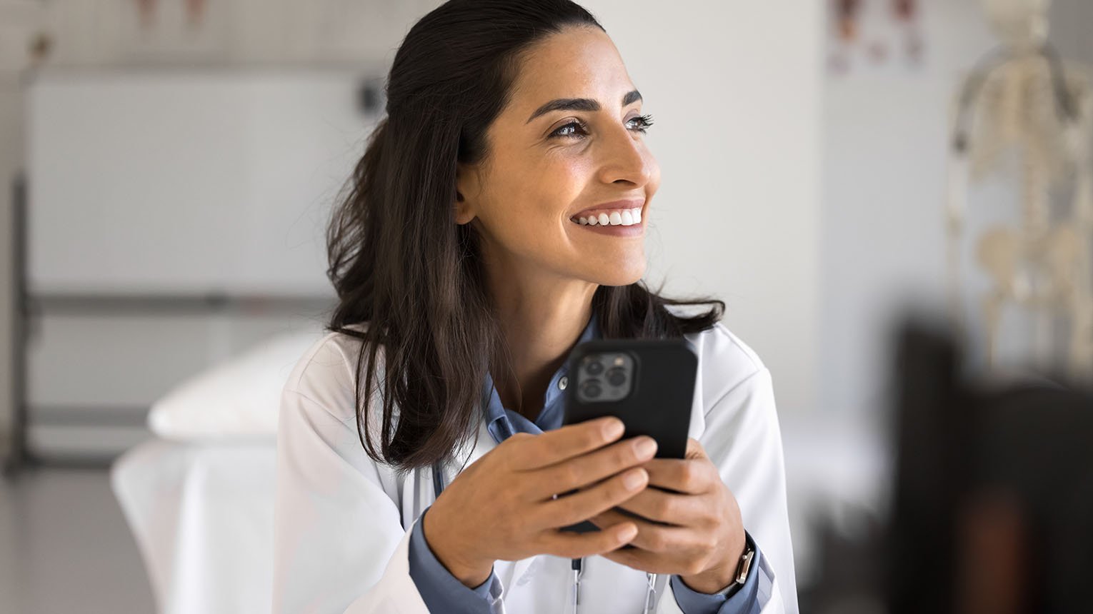 A smiling doctor holding her mobile phone