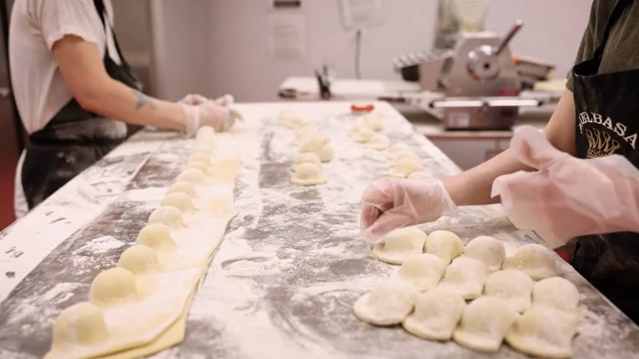 handmade pierogis being rolled out on long countertop