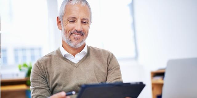 a male hispanic business owner reading about employee benefits from paychex