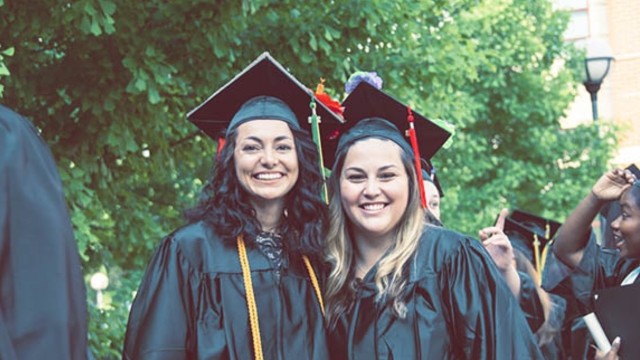 2 female college graduates stand side by side