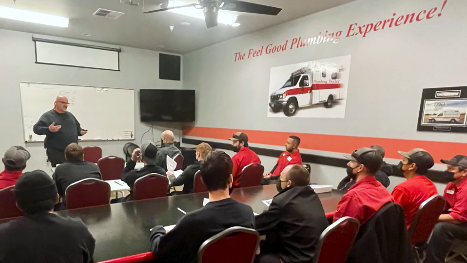 company of workers in red shirts hearing presentation