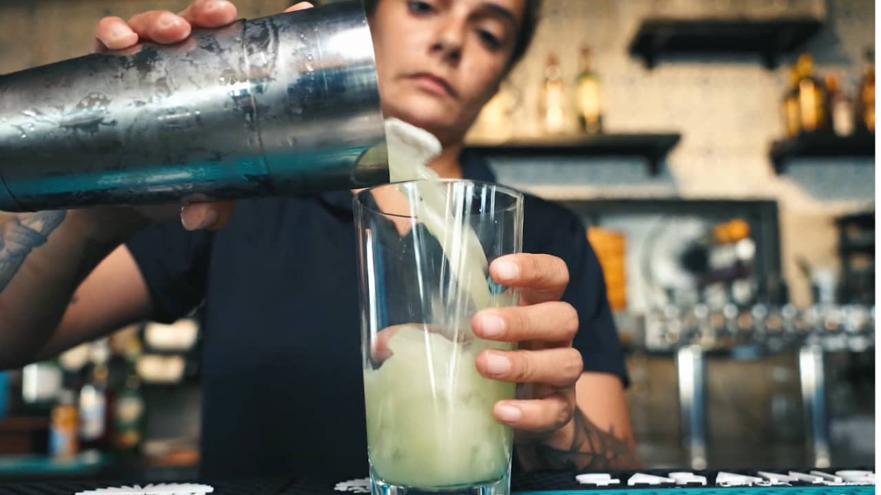 bartender pours mixed drink into glass at Lago 210 restaurant