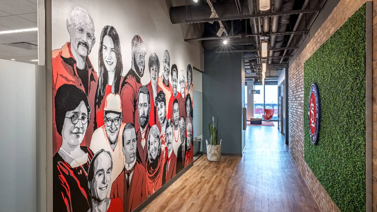 colorful artwork of individuals in life size scale along hallway opposite green wall
