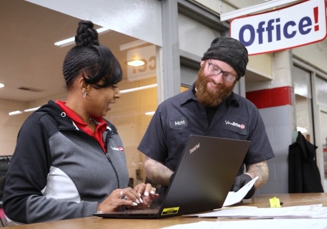 female and male staff at service desk of auto dealership